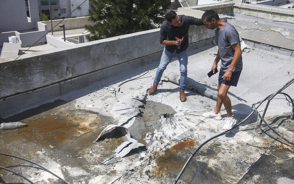 Un journaliste interrogeant un homme, à droite, dont la maison a été touchée par une roquette tirée depuis la bande de Gaza par le groupe terroriste palestinien du Jihad islamique, à Sderot, dans le sud du pays, le 6 août 2022. (Crédit : Yonatan Sindel/Flash90)