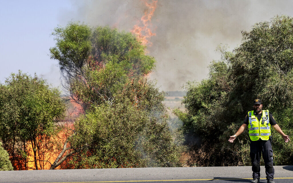 Des policiers israéliens sur le lieu d'un incendie provoqué par une roquette tirée depuis la bande de Gaza qui a touché un champ près de Sderot, dans le sud d'Israël, le 7 août 2022. (Crédit : Yossi Zamir/Flash90)