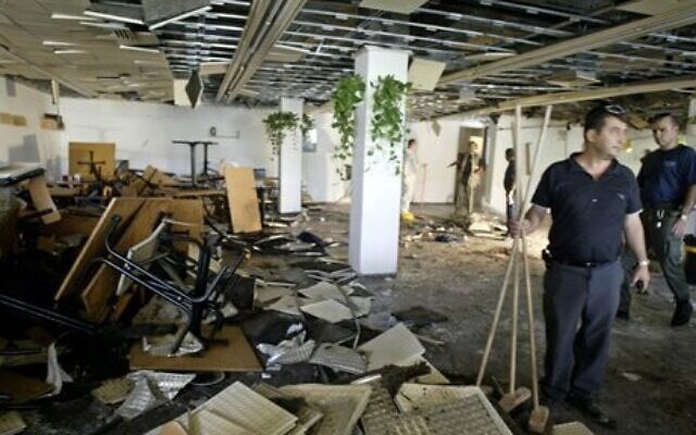 Des employés nettoient l'intérieur d'une cafétéria, quelques heures après l'explosion d'une bombe à l'Université hébraïque de Jérusalem, qui a fait neuf morts, dont quatre Américains, et plus de 70 blessés, le 31 juillet 2002. (Crédit : AP Photo/David Guttenfelder)