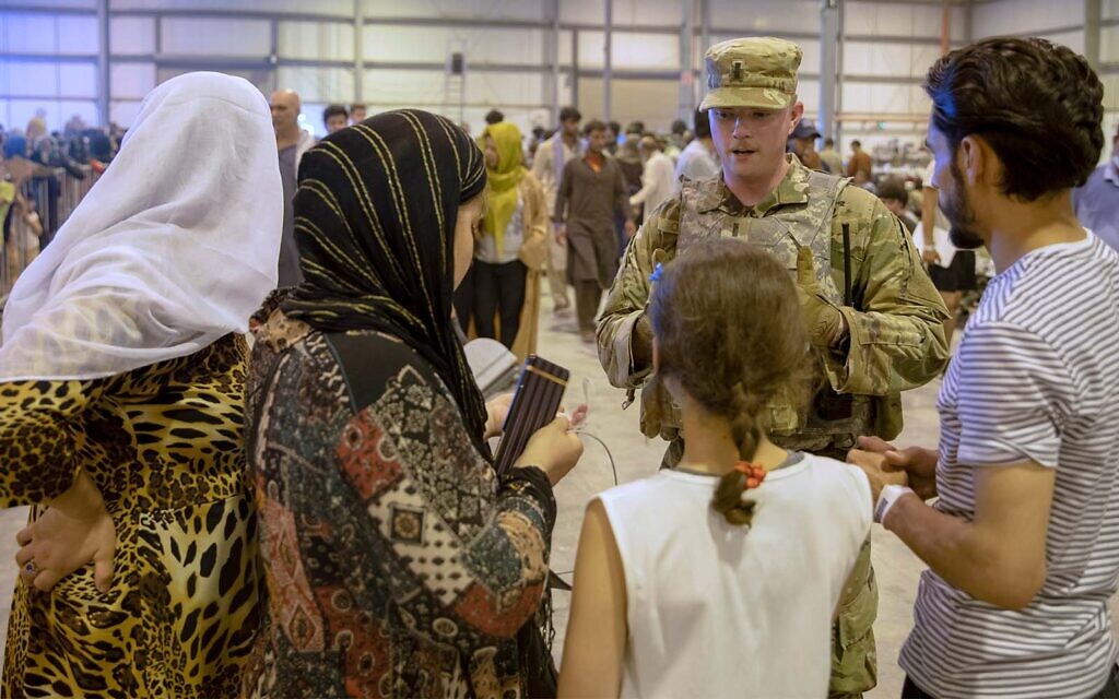 Un aviateur apportant son aide à des personnes évacuées d'Afghanistan, à la base aérienne d'Al Udeid, au Qatar, le 26 août 2021. (Crédit : Sergent-chef True Thao/U.S. Army via AP/Archives)
