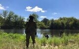 Un soldat ukrainien surveille les alentours tandis que des vivres sont acheminés sur l'autre rive de la rivière Siverskyi Donets, près de Zadonets’ke, le 29 juillet 2022 (Lazar Berman/The Times of Israel)