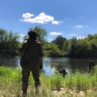 Un soldat ukrainien surveille les alentours tandis que des vivres sont acheminés sur l'autre rive de la rivière Siverskyi Donets, près de Zadonets’ke, le 29 juillet 2022 (Lazar Berman/The Times of Israel)