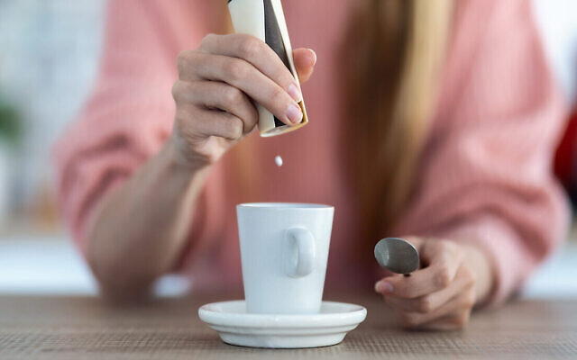 Illustration : Une personne ajoutant de l'édulcorant à son café. (Crédit : Nensuria via iStock by Getty Images)