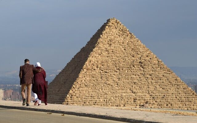 Un couple marche à côté des pyramides de Giza, au sud-ouest de la capitale égyptienne du Caire, le 29 décembre 2018. (Crédit :  MOHAMED EL-SHAHED / AFP)