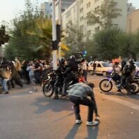 Un officier de police iranien levant une matraque pour disperser des manifestants lors d'une manifestation pour Mahsa Amini, une femme décédée après avoir été arrêtée à Téhéran le 19 septembre 2022. (Crédit : AFP)