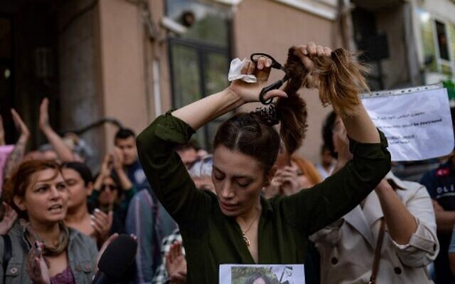 Nasibe Samsaei, une Iranienne vivant en Turquie, coupe sa queue de cheval lors d'une manifestation devant le consulat d'Iran à Istanbul le 21 septembre 2022, suite à la mort d'une Iranienne après son arrestation par la police des mœurs du pays à Téhéran.(Crédit : Yasin AKGUL / AFP)