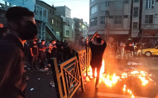 Des manifestants mettent le feu à une barricade qui bloque une rue lors d'une manifestation suite à la mort d'une femme détenue par la police des mœurs, dans le centre-ville de Téhéran, en Iran, le 21 septembre 2022, sur une photo prise par un individu non employé par l'AFP et obtenue par l’agence hors d'Iran. (Crédit : AFP)