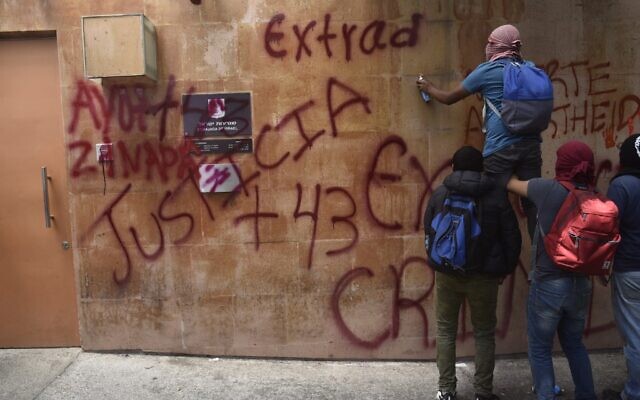 Des étudiants d'Ayotzinapa peignent des slogans sur les murs de l'ambassade d'Israël à Mexico lors d'une manifestation le 21 septembre 2022 pour demander l'extradition de l'ancien procureur général Tomas Zeron de Lucio. (Crédit : CLAUDIO CRUZ / AFP)