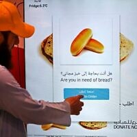 Un homme commandant des articles dans un distributeur automatique qui distribue du pain gratuit, à Dubaï, le 22 septembre 2022. (Crédit : Karim Sahib/AFP)
