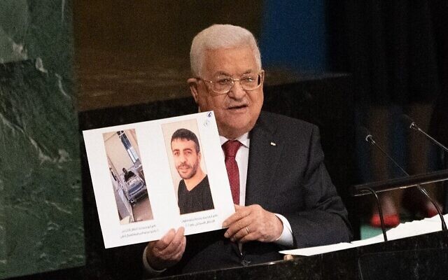 Le chef de l’Autorité palestinienne, Mahmoud Abbas, brandit des photos du terroriste palestinien emprisonné Nasser Abu Hamid, qui souffre d'un cancer, alors qu’il s’adresse à la 77e session de l’Assemblée générale des Nations Unies à New York le 23 septembre 2022. (Crédit : Bryan R. Smith/AFP)
