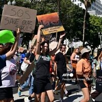 Des jeunes et des militants de Los Angeles tenant des pancartes alors qu'ils participent à une grève mondiale pour le climat visant à déclarer une urgence de justice climatique devant l'hôtel de ville de Los Angeles, le 23 septembre 2022.
(Crédit : Frederic J. Brown/AFP)