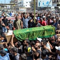 Des personnes en deuil marchant avec le corps d'une des victimes qui s'est noyée dans le naufrage d'un bateau de migrants qui a coulé au large des côtes syriennes, lors de ses funérailles après le retour de son corps dans le camp de réfugiés de Nahr al-Bared, dans la banlieue de la ville de Tripoli, dans le nord du Liban, le 24 septembre 2022. (Crédit : Fathi al-Masri/AFP)