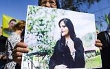 Une femme brandit une pancarte représentant une photo de Mahsa Amini, 22 ans, une Iranienne décédée alors qu'elle était détenue par les autorités iraniennes, lors d'une manifestation de solidarité dans la ville de Hasakeh, dans le nord-est de la Syrie, le 25 septembre 2022. (Crédit : Delil SOULEIMAN/AFP)