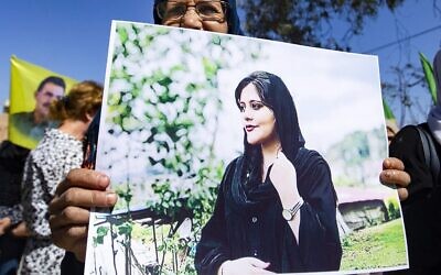 Une femme brandit une pancarte représentant une photo de Mahsa Amini, 22 ans, une Iranienne décédée alors qu'elle était détenue par les autorités iraniennes, lors d'une manifestation de solidarité dans la ville de Hasakeh, dans le nord-est de la Syrie, le 25 septembre 2022. (Crédit : Delil SOULEIMAN/AFP)