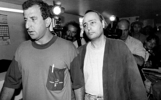 Eddie Antar, à droite, connu dans le passé sous le nom de ‘Crazy Eddie,’ roi de l'électronique de New York, escorté par un enquêteur de la police israélienne à Petah Tikva, en Israël, le 25 juin 1992. (Crédit : Sven Nackstrand/AFP via Getty Images/ via JTA)