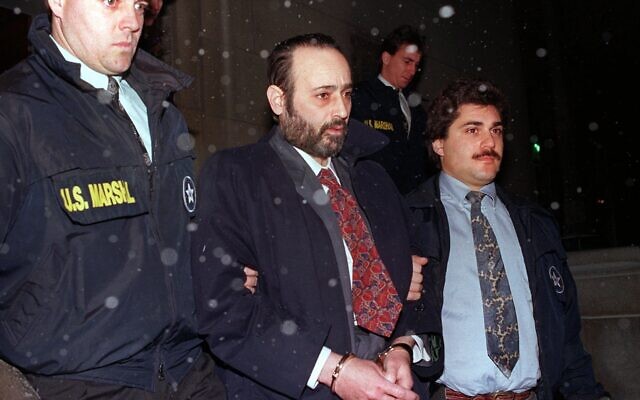 "Crazy" Eddie Antar, au centre, fondateur de la chaîne de magasins électroniques Crazy Eddie, porte des menottes après avoir été extradé d'Israël, le 11 janvier 1993. (Crédit :  AP Photo/Dan Hulshizer, file)