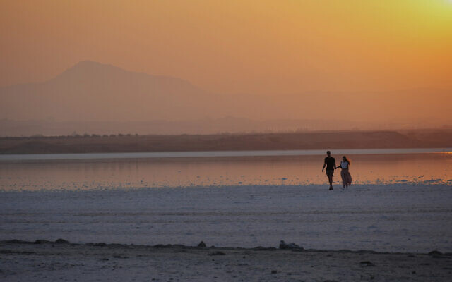 Un couple se promenant au lac salé pendant le coucher du soleil dans la ville côtière du sud-est de Larnaca, dans l'île méditerranéenne orientale de Chypre, le 5 septembre 2022. (Crédit : AP/Petros Karadjias/Dossier)