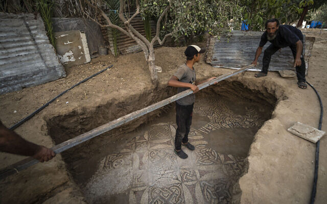 Des Palestiniens nettoient autour d'un sol en mosaïque de l'époque byzantine, récemment découvert par un agriculteur à Bureij, dans le centre de la bande de Gaza, le 5 septembre 2022. (Crédit : AP Photo/Fatima Shbair)