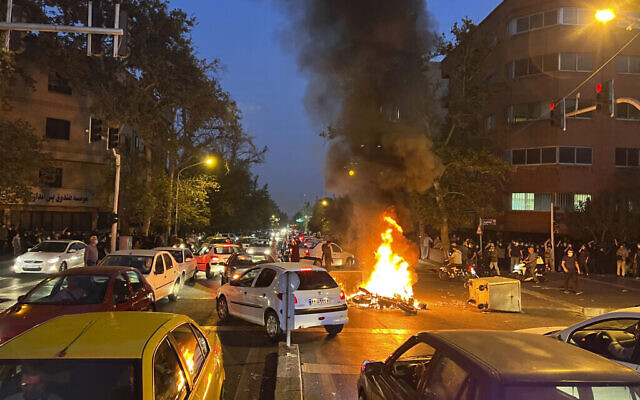 Une moto de la police brûle, dans le centre-ville de Téhéran, lors d’une manifestation contre la mort de Mahsa Amini, le 19 septembre 2022. (Crédit : AP Photo)