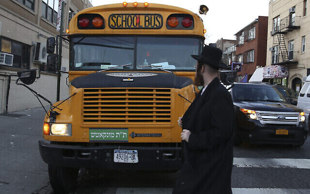 Illustration : Un homme traverse devant un bus scolaire avec une inscription en yiddish à Borough Park, à Brooklyn, New York, le 1er janvier 2014. (Crédit : Nati Shohat/Flash 90)