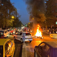 Une moto de police brûle pendant une manifestation, dans le centre de Téhéran, en Iran, le 19 septembre 2022. (Crédit : AP Photo)