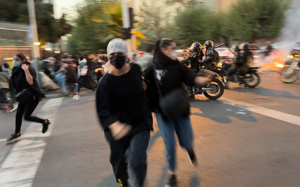 Des femmes fuient la police anti-émeute pendant une manifestation contre la mort d'une jeune femme placée en détention pour avoir contrevenu au code vestimentaire strict du pays, dans le centre de Téhéran, en Iran, le 19 septembre 2022. (Crédit : AP Photo)