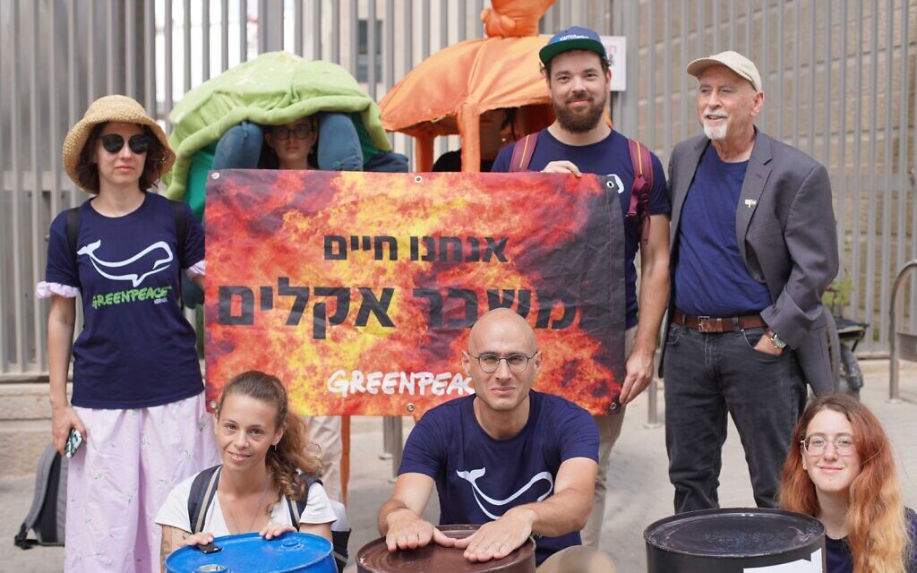 Violetta Ryabko, à l'extrême gauche, portant un chapeau et des lunettes de soleil, et son mari Vasily Yablokov, debout, deuxième à partir de la droite, se joignant au législateur Alon Tal, debout à droite, au directeur de Greenpeace Israël Jonathan Aikhenbaum, assis au centre et à d'autres militants, lors d'une manifestation de Greenpeace contre la politique israélienne en matière de gaz naturel, à Jérusalem, le 20 septembre 2022. (Crédit : Greenpeace)