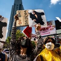 Des personnes scandent des slogans et tiennent les photos de Mahsa Amini lors de la manifestation "Freedom rally for Iran" dans le quartier de Shibuya à Tokyo, le 1er octobre 2022. (Crédit : Philip FONG / AFP)