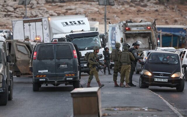 Alors que l'armée mène une chasse à l'homme pour retrouver le tireur présumé de l'attaque meurtrière du 8 octobre 2022, au cours de laquelle une soldate a été tuée, des officiers s’entretiennent avec des passagers dans la circulation, après avoir fermé une entrée de la ville palestinienne d'Anata en Cisjordanie, le 9 octobre 2022. (Crédit : Ahmad Gharabli/AFP)