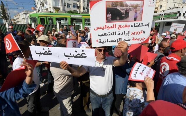 Des partisans du parti Destourien brandissant des drapeaux nationaux et levant des pancartes lors d'une manifestation contre le président Kais Saied, dans la capitale Tunis, le 15 octobre 2022. (Crédit : Fethi Belaid/AFP)