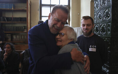 Arnold Schwarzenegger, à gauche, serre dans ses bras Lydia Maksimovicz, survivante de la Shoah, à droite, à Auschwitz, en Pologne, le 28 septembre 2022. (Crédit : AP Photo/Michal Dyjuk)