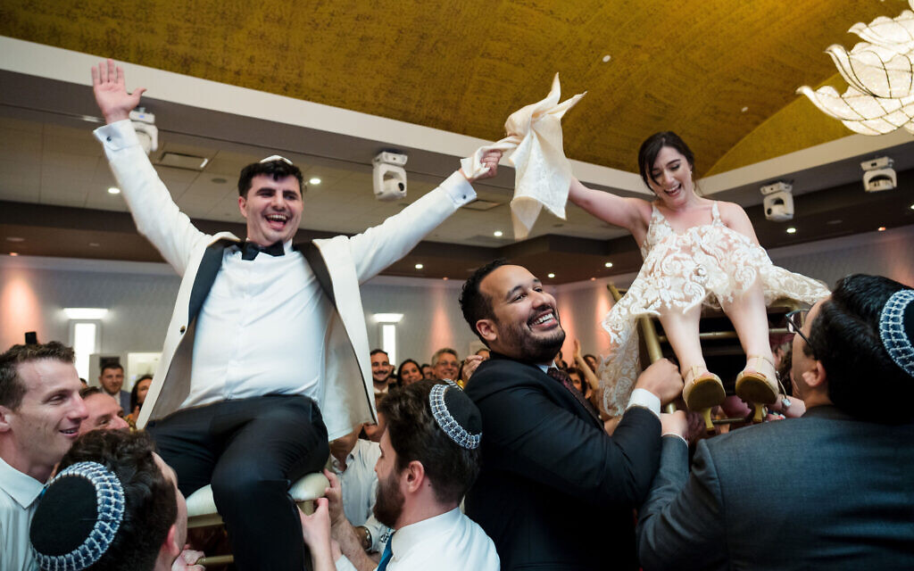 Alex Zeldin et Tamar Caplan sont soulevés sur des chaises pendant leur réception de mariage, le 21 août 2022. (Crédit : JC Lemon Photography/JTA)