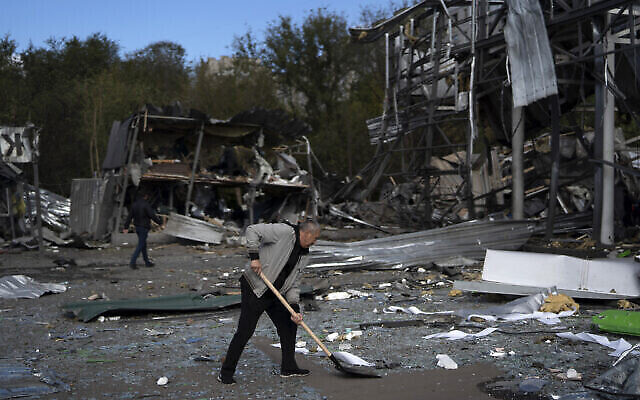 Illustration : Une personne nettoie les débris d’un magasin d’automobiles détruit après une attaque russe à Zaporizhzhia, en Ukraine, le 11 octobre 2022. (Crédit : Leo Correa/AP)