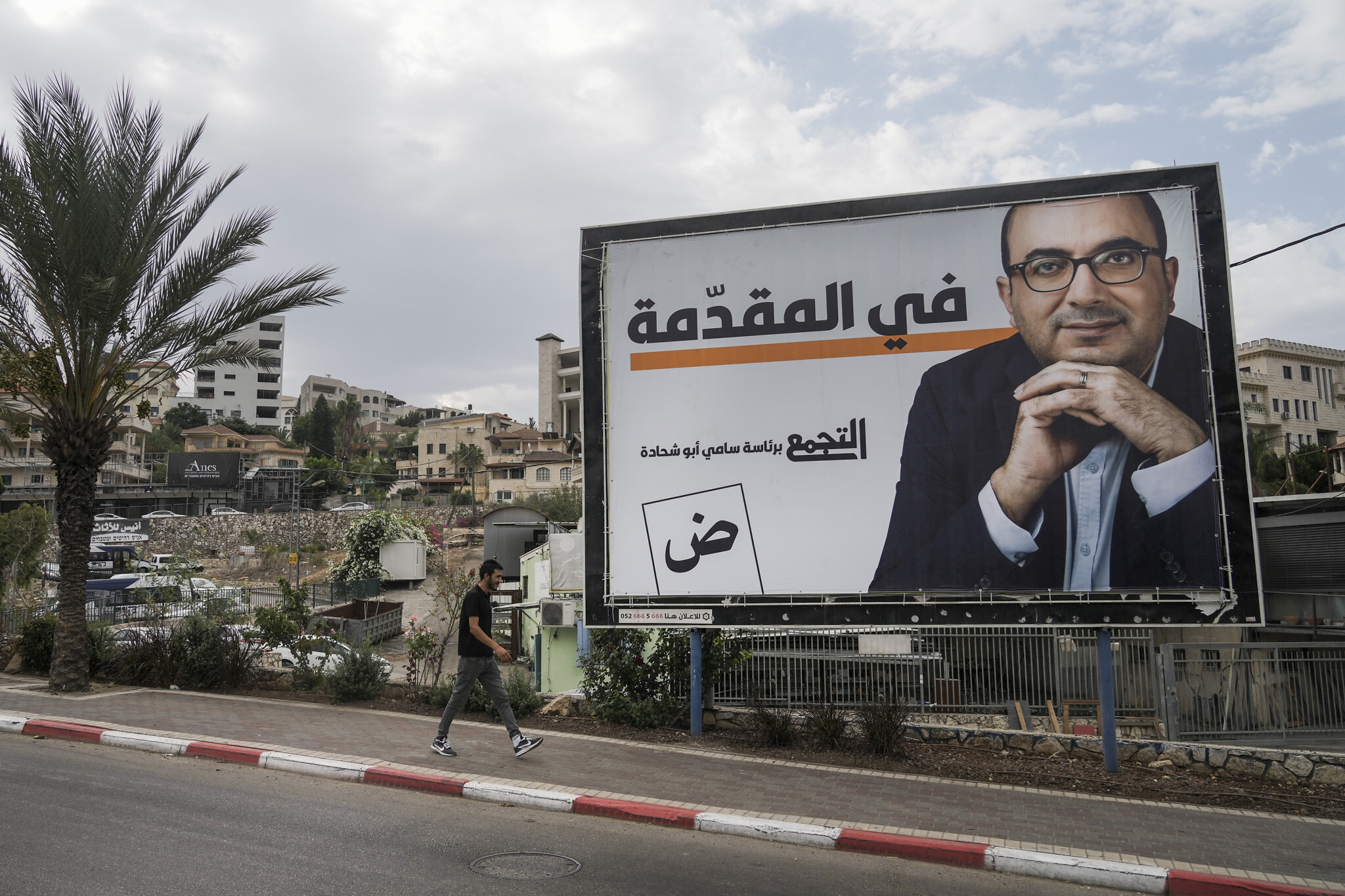 Un homme passe devant un panneau de campagne qui montre Sami Abu Shehadeh, chef du parti nationaliste Balad, à Umm al-Fahm, dans le nord d'Israël, le 21 octobre 2022. (Crédit : AP/Mahmoud Illean)