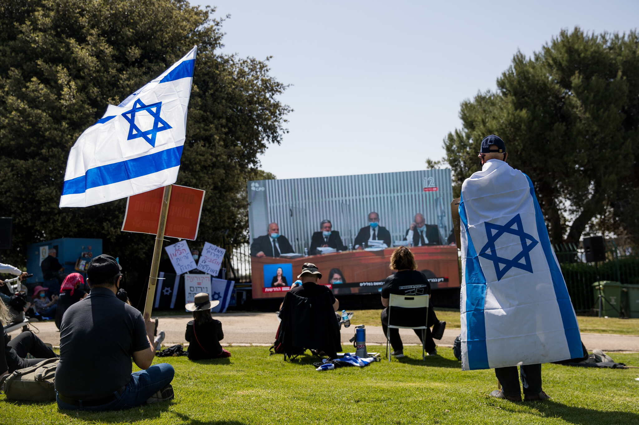 Des Israéliens regardent une audience de la Cour suprême aux abords de la Knesset, le 3 avril 2020. (Crédit :  Yonatan Sindel/Flash90)