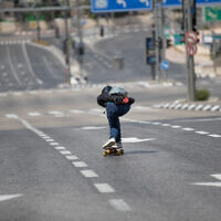 Un Israélien fait du skate-board sur une route vide de Jérusalem pour Yom Kippour, le 16 septembre 2021. (Crédit : Flash90)