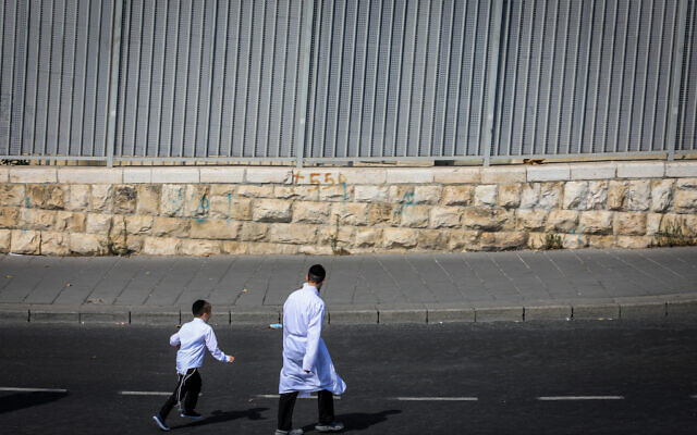 Des personnes marchant sur une route vide le jour de Yom Kippour, à l'entrée de Jérusalem, le 5 octobre 2022. (Crédit : Jamal Awad/Flash90)