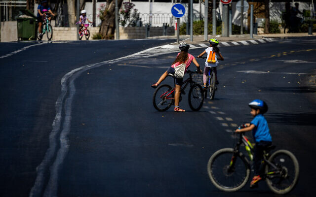 Des personnes faisant du vélo et marchant le long de la route vide, le jour de Yom Kippour, la plus sainte des fêtes juives, à Jérusalem, le 4 octobre 2022. (Crédit : Yonatan Sindel/Flash90)