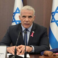 Le Premier ministre Yair Lapid, portant un ruban rose pour la sensibilisation au cancer du sein, dirigeant la réunion hebdomadaire du cabinet au bureau du Premier ministre, à Jérusalem, le 2 octobre 2022. (Crédit : Amos Ben Gershon/GPO)