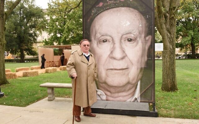Judah Samet à côté de son portrait, dans le cadre du projet Lest We Forget de Luigi Toscano à l’Université de Pittsburgh en 2019. (Crédit : Photo par Hector Corante, gracieuseté du Centre pour la Shoah de Pittsburgh via la JTA)