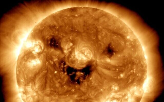 Une image du soleil avec des trous coronaux formant un visage souriant. (Crédit : NASA)