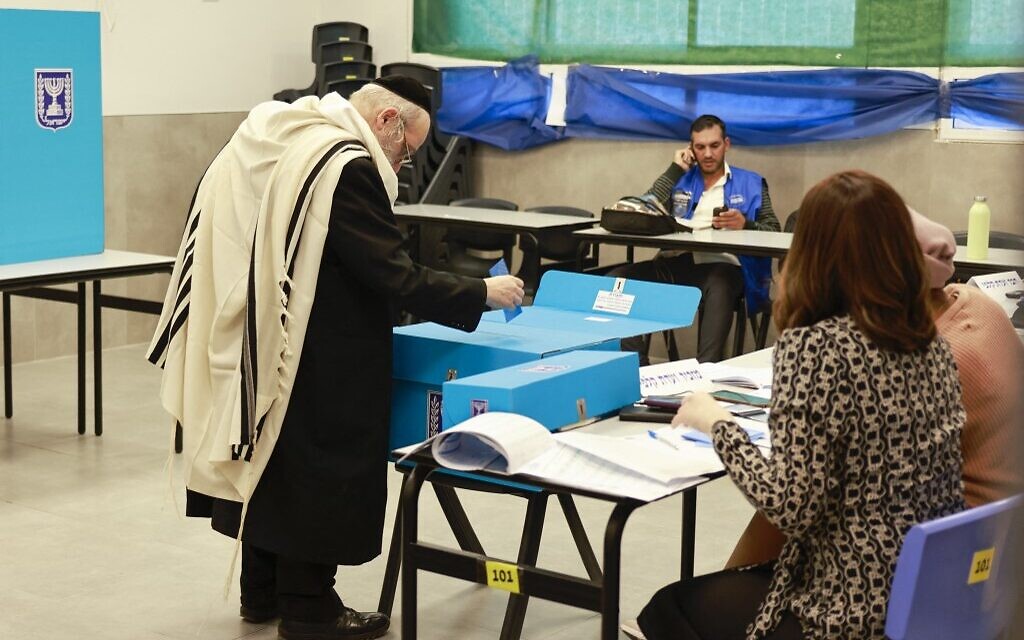 Un électeur juif ultra-orthodoxe dépose son bulletin de vote dans un bureau de vote à Bnei Brak, le 1er novembre 2022. (Crédit : Menahem KAHANA / AFP)