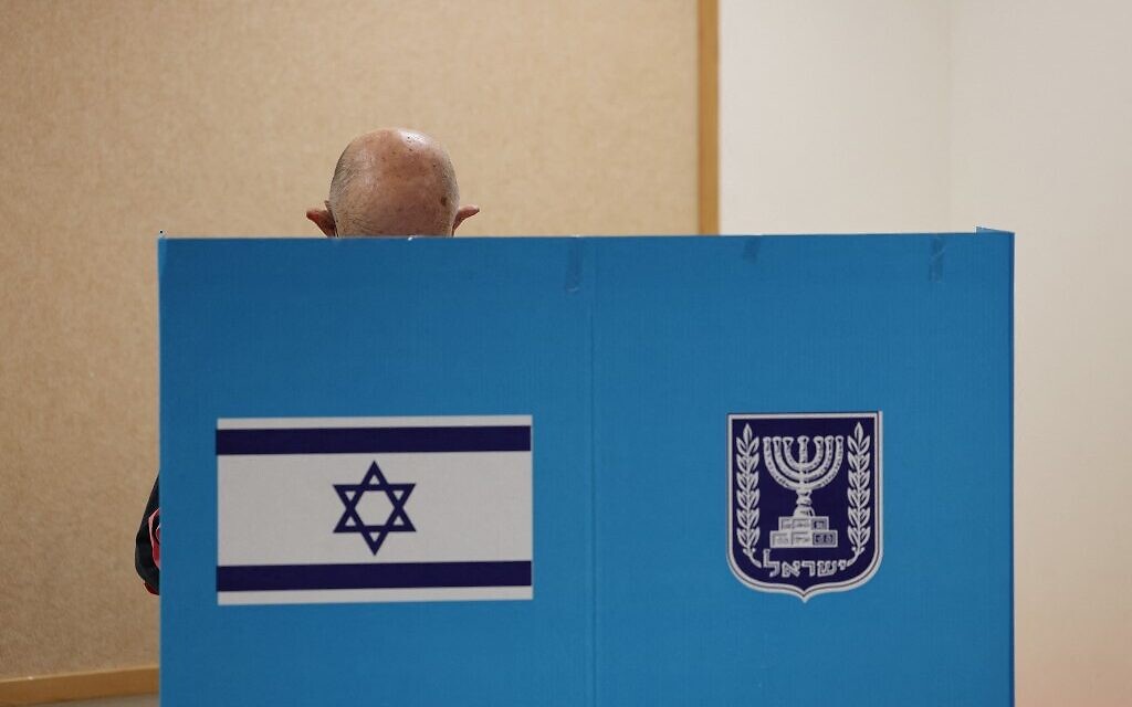 Un électeur israélien dépose un bulletin de vote lors de la cinquième élection d'Israël en moins de quatre ans dans un bureau de vote de Tel Aviv, le 1er novembre 2022. (Crédit : Jack Guez/Pool Photo via AP)