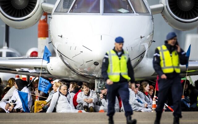 Des membres de Milieudefensie, Extinction Rebellion, Greenpeace et d'autres organisations sont assis devant un avion lors d'une manifestation "SOS pour le climat" à l'aéroport de Schiphol, près d'Amsterdam, le 5 novembre 2022. (Crédit : Remko de Waal / ANP / AFP)