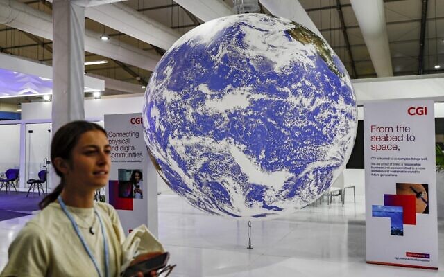 Un participant passe devant une maquette du globe terrestre au Centre international de conventions de Sharm el-Sheikh, le premier jour du sommet sur le climat COP27, dans la station balnéaire égyptienne de Sharm el-Sheikh, sur la mer Rouge, le 6 novembre 2022. (Crédit : Mohammed ABED / AFP)