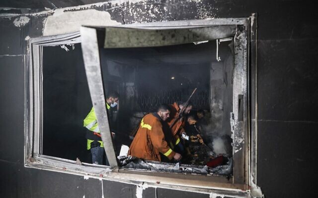 Des pompiers palestiniens éteignent les flammes dans un appartement ravagé par un incendie dans le camp de Jabaliya, dans le nord de la bande de Gaza, le 17 novembre 2022. (Crédit : MAHMUD HAMS / AFP)
