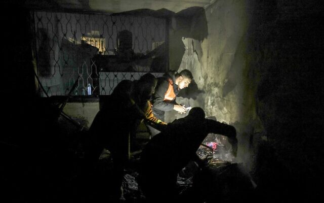 Des pompiers palestiniens éteignent les flammes dans un appartement ravagé par un incendie dans le camp de Jabaliya, dans le nord de la bande de Gaza, le 17 novembre 2022. (Crédit : MAHMUD HAMS / AFP)