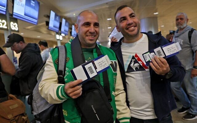 Des fans de football montrent leurs passeports israéliens et leurs billets d'avion alors qu'ils se préparent à embarquer sur un vol de l'aéroport Ben Gurion de Tel Aviv vers Doha pour assister à la Coupe du monde 2022, le 20 novembre 2022. (Crédit : Gil COHEN-MAGEN / AFP)