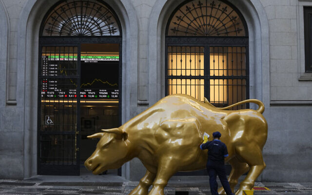 Un ouvrier nettoie un signe de protestation sur le Golden Bull, une réplique du Charging Bull de Wall Street, à l'extérieur de la Bourse brésilienne B3 à Sao Paulo, au Brésil, mercredi 17 novembre 2021. (Crédit : Andre Penner/AP)