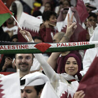 Des supporters agitent le drapeau palestinien et applaudissent avant le match de la Coupe du monde de football entre le Qatar et l'Équateur au stade Al Bayt à Al Khor, le 20 novembre 2022. (Crédit : Ariel Schalit/AP)